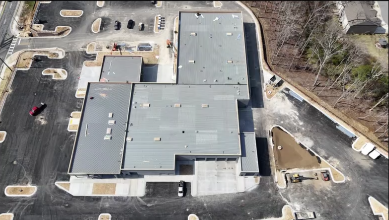 Construction crews and cranes working on the exterior glass framing and facade of the new Mercedes-Benz dealership..png